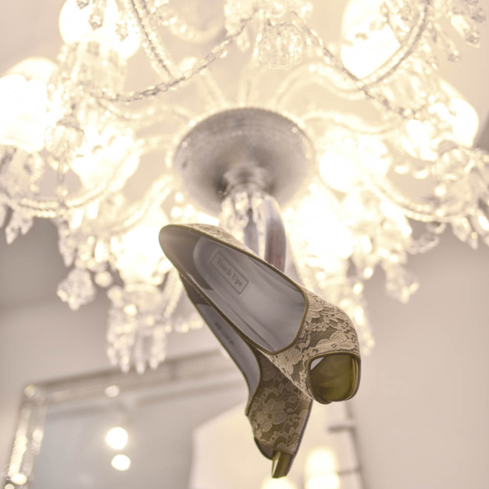 Photo of bridal shoes hanging in crystal chandelier in castle in Germany